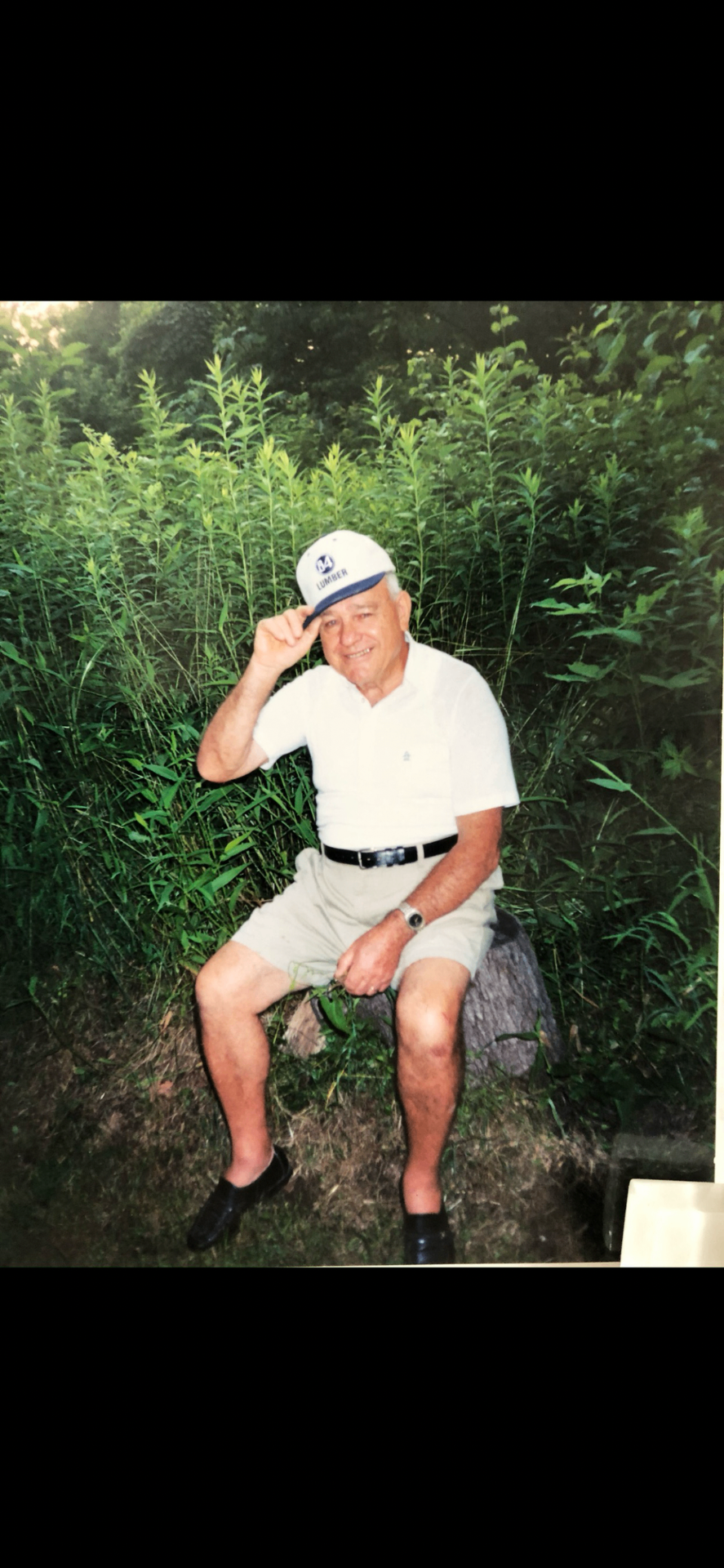 Romualdo Magnelli seated outdoors among tall summer greenery
