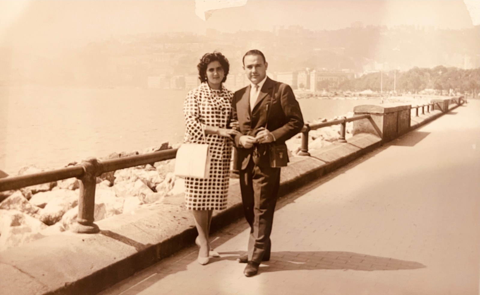 A young couple standing together on a seafront promenade in Italy