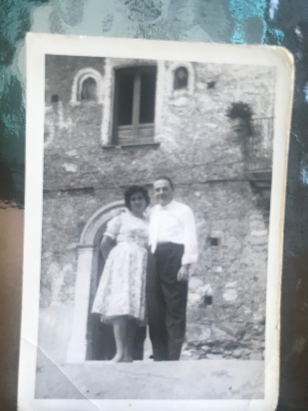 A black and white photograph of a couple standing outside a stone village house